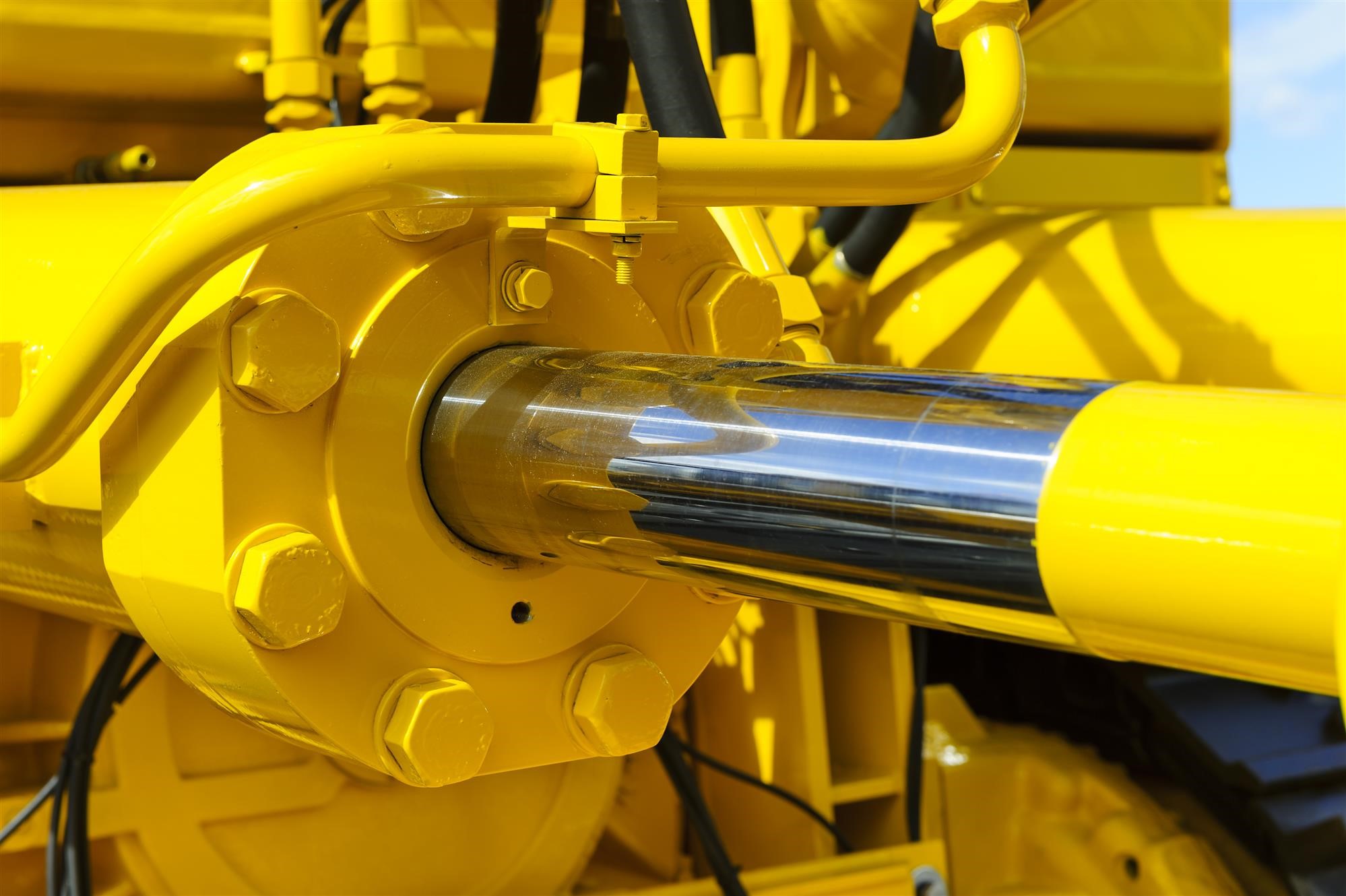 Engineer inspecting hydraulic hoses on heavy construction equipment.