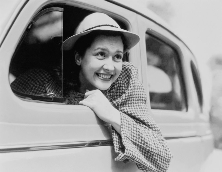 woman enjoying road trip and looking out from car window